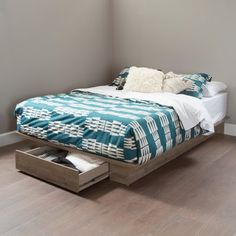 a bed sitting on top of a hard wood floor next to a white and blue comforter