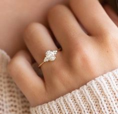 a woman's hand wearing a gold ring with a white flower on the middle