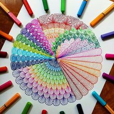 colored crayons are arranged in the shape of a peacock's tail on top of a white paper