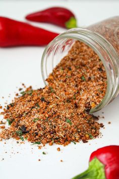 a jar filled with spices sitting on top of a white table next to red peppers