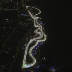 an aerial view of a city at night with lights on the road and buildings in the background