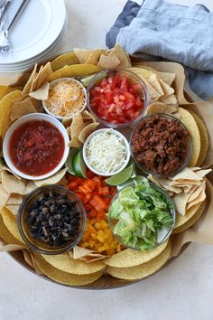 a plate filled with tacos, salsa and tortilla chips on top of a table