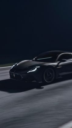 a black sports car driving on the road at night