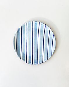 a blue and white striped plate sitting on top of a table next to a wall