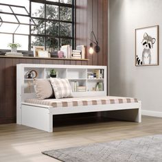 a white bed with a book shelf above it in a room next to a window