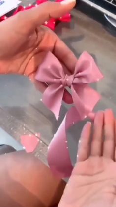 a person is holding a pink bow in their left hand and the other hand is pointing at it