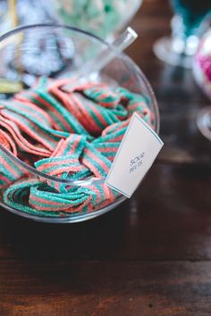 a bowl filled with colorful yarn on top of a wooden table next to other items