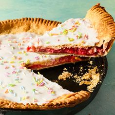 a pie with white frosting and sprinkles on it is cut in half