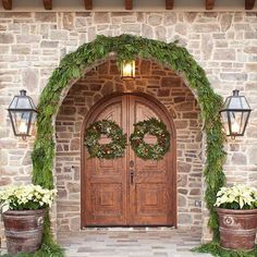 two large wooden doors with wreaths on them and some lights hanging from the ceiling