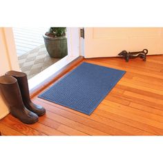 a pair of rubber boots sitting on top of a wooden floor next to a door