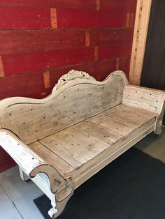 an old white wooden bench sitting in front of a red wood paneled wall and floor