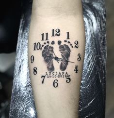 a black and white photo of a clock with two baby feet on it's arm