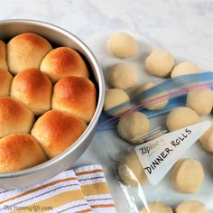 rolls in a metal bowl next to a package of dinner rolls on a white table