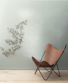 a chair sitting on top of a hard wood floor in front of a wall with flowers