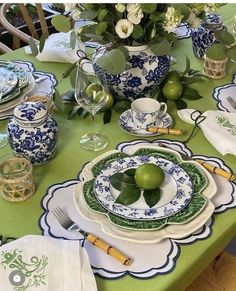 a green table topped with plates and bowls filled with limes on top of each other