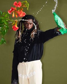 a woman with dreadlocks holding a green bottle and sprinkles on her face