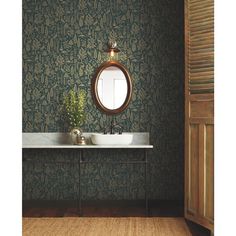 a bathroom with green wallpaper and a white sink in front of a round mirror