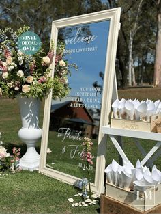 there is a mirror and some flowers on the grass near a sign that says welcome