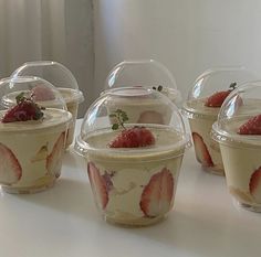 several plastic cups with strawberries in them sitting on a white counter top next to a window