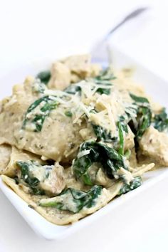 a white plate topped with pasta covered in spinach