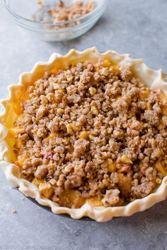 a pie crust with meat in it on a table next to a bowl of nuts