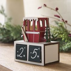 a small wooden house on top of a table with the numbers twenty and five in front of it