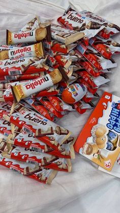 a pile of candy bars sitting on top of a white bed next to each other