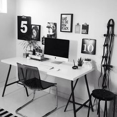 a white desk with black chairs and pictures on the wall above it, next to a wooden door