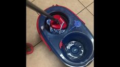 a red and blue toy car with wheels on the floor next to a bowl filled with water