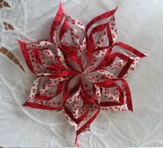 a red and white paper flower sitting on top of a sheet of cloth next to scissors