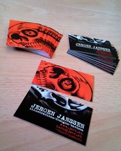 four business cards on a wooden table with an orange and black design in the middle