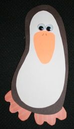 a paper cut out of a penguin sitting on top of a black surface with eyes wide open