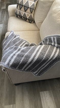 a gray and white striped blanket sitting on top of a couch next to a pillow