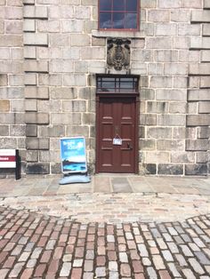 a brick building with a door and sign on the sidewalk