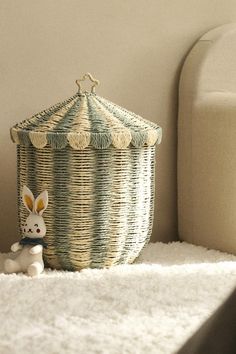 a toy rabbit sitting next to a wicker basket on the floor in front of a white couch