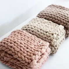 three knitted blankets sitting next to each other on top of a white countertop