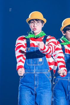 two young boys dressed in overalls and hats