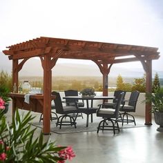 an outdoor dining table and chairs under a wooden pergolan with pink flowers in the foreground