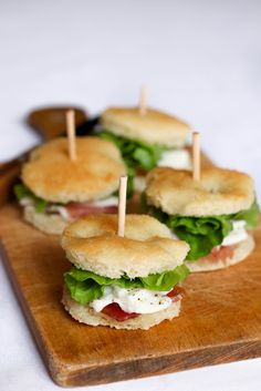 mini sandwiches with toothpicks in them sitting on a cutting board, ready to be eaten