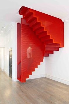 a red staircase in the middle of a room with white walls and wood floors, on instagram