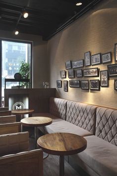 a restaurant with wooden tables and white couches in front of a wall full of framed pictures