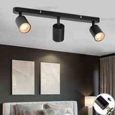 three lights are on the ceiling above a bed in a room with black walls and curtains