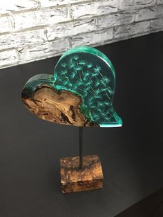 a green glass sculpture sitting on top of a wooden stand