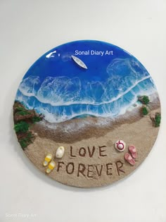 a plaque with the words love forever written in sand and seashells on it