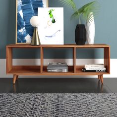 a wooden shelf with books and vases on it in front of a blue wall