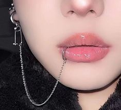 a close up of a woman with piercings on her nose and necklace around her neck