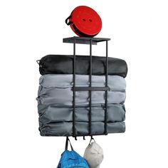 an iron rack holding several folded blankets and a red hat on top of it,