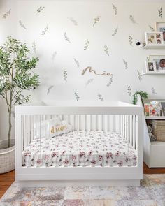 a baby's room with a white crib and floral wallpaper