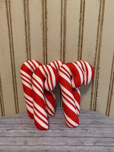 two red and white candy canes sitting on top of a wooden table next to a wall