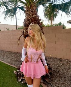 a woman in a short pink dress and white socks posing for the camera with her hands on her hips